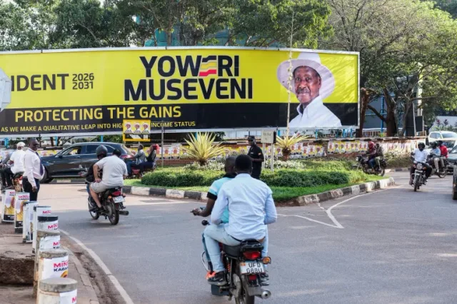 Motorcycles and cars on a street in Kampala near a large election billboard, file photo