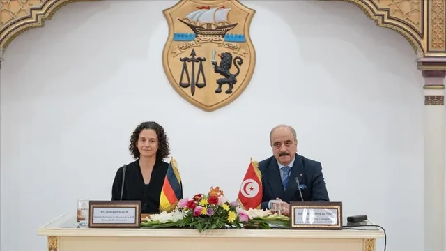 The emblem of the Tunisian Republic on a white wall behind an official table with Tunisian and German flags, file photo