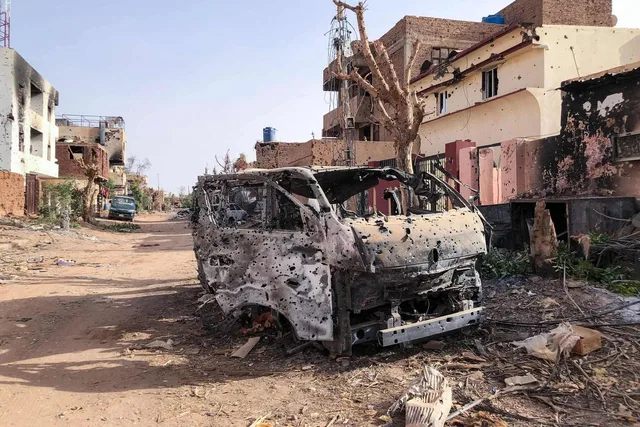 Burnt-out, bullet-riddled vehicle on a war-damaged street in Sudan, file photo