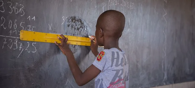 A pupil drawing a line with a yellow ruler on a blackboard covered with numbers, file photo