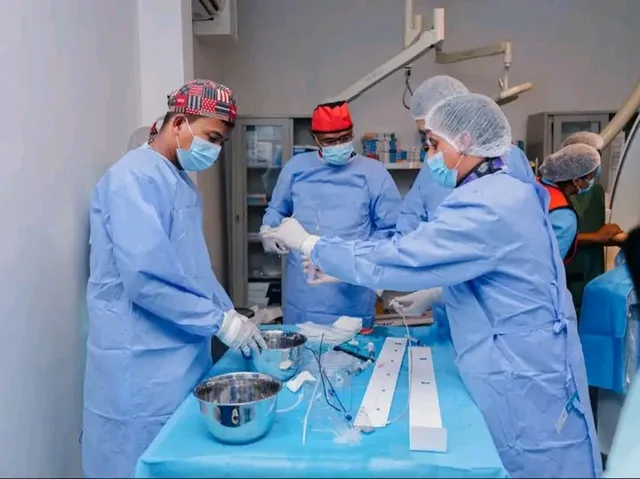 Doctors in surgical gowns prepare equipment in a catheterisation room