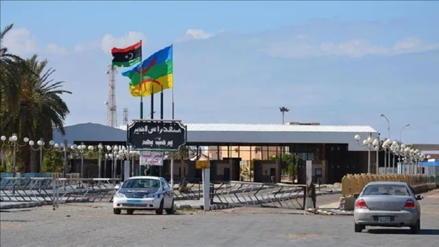 Entrance of the Ras Jedir border crossing on the Libyan side, with the Libyan flag and two cars in front of the gate, file photo
