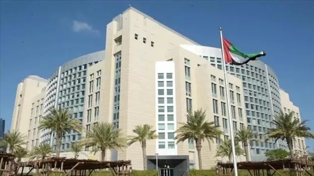 A large government building with the UAE flag flying in front, surrounded by palm trees, in Abu Dhabi, file photo
