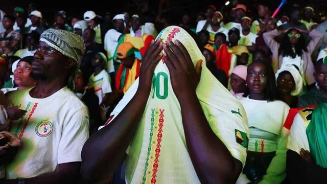A crowd of Senegal supporters in national team shirts, one covering his face with a shirt, file photo