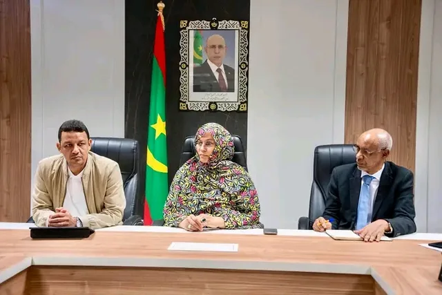 The health minister flanked by two officials at a meeting table