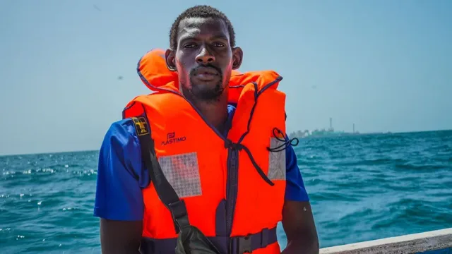 A fisherman wearing an orange life jacket aboard a boat at sea, file photo