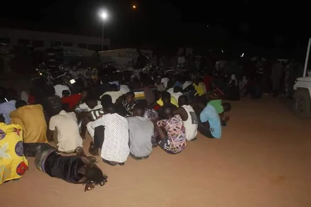 People sitting on the ground at night in a yard during a police operation in Niger, file photo