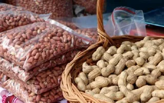 A wicker basket of groundnuts in their shells beside bags of shelled groundnuts, illustrative file photo