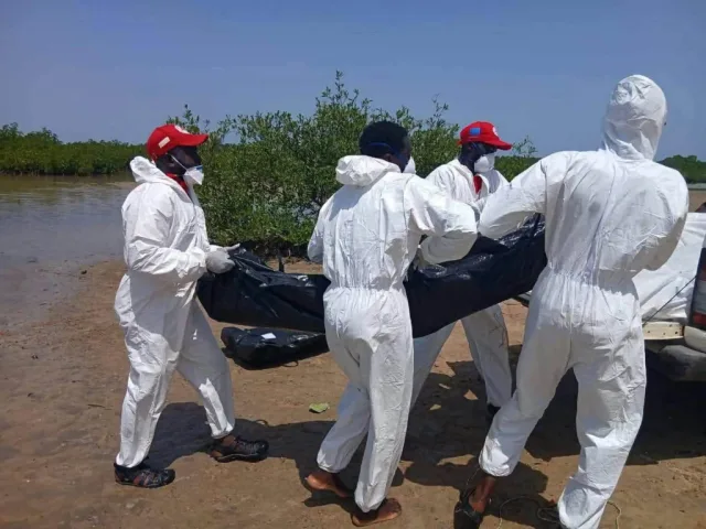 Red Cross volunteers carrying a body