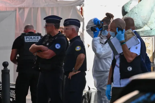 French police officers and a forensic expert taking photos at an investigation site, file photo