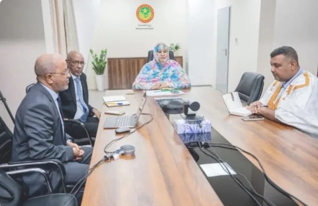The health minister chairs a meeting at a table with three officials