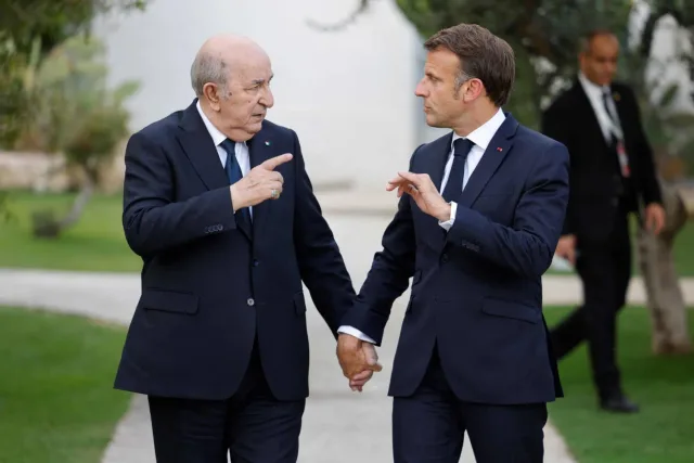 Abdelmadjid Tebboune and Emmanuel Macron walking side by side in a garden