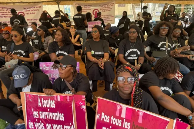 Women dressed in black hold placards against violence on women during a protest in Dakar