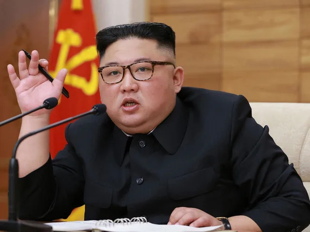 North Korean leader Kim Jong Un speaks behind two microphones holding a pen, file photo