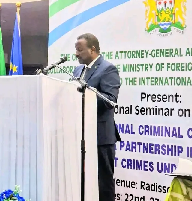 The justice minister speaks at the podium in front of the ICC regional seminar banner