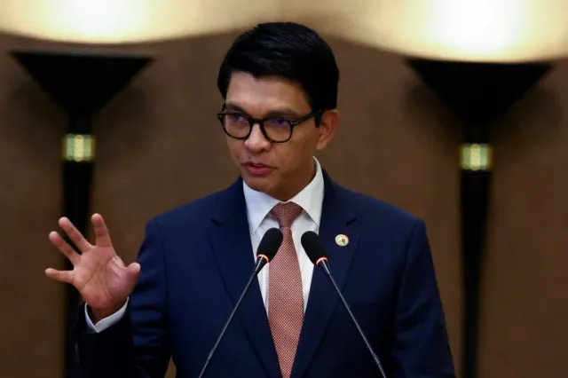 Andry Rajoelina speaking in front of two microphones, wearing a blue suit and glasses, file photo