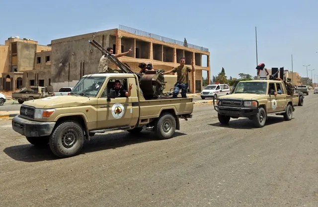 Two armed pickup trucks carrying fighters on a street in western Libya, file photo