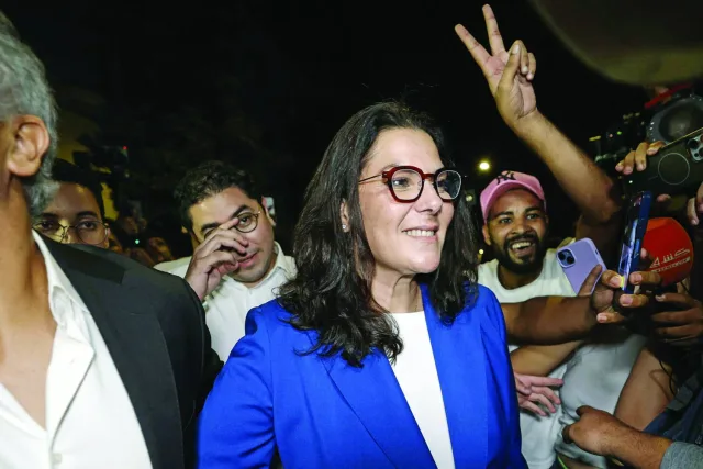 Fatima-Zahra El Mansouri in a blue jacket and glasses surrounded by supporters
