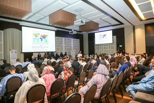 Participants seated in a conference hall facing screens