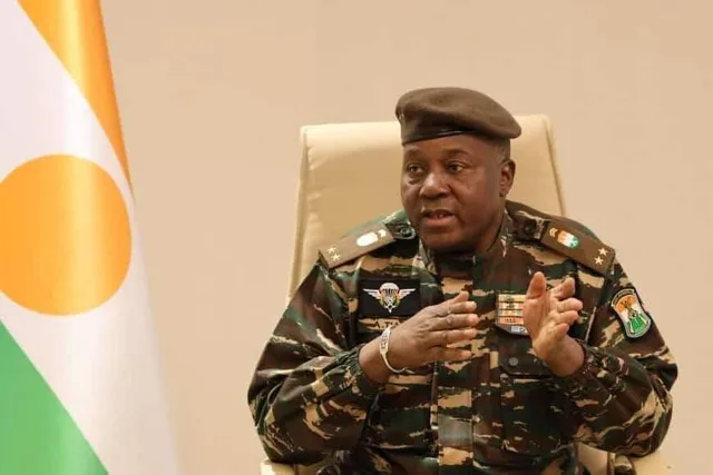 General Abdourahamane Tiani in military uniform in front of the Niger flag