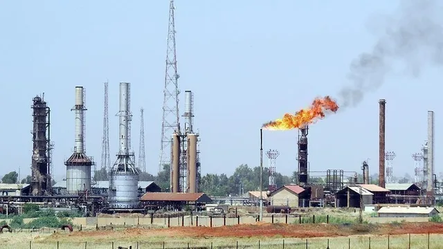 An oil facility with towers, tanks and a burning gas flare under a clear sky, illustrative file image