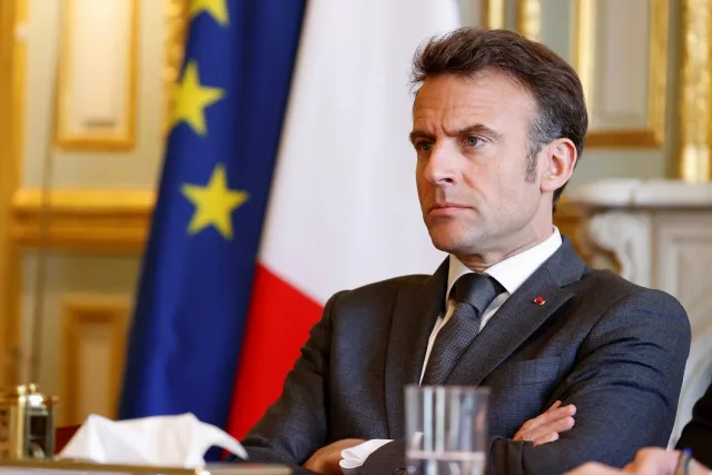 French President Emmanuel Macron seated in front of French and European flags, file photo