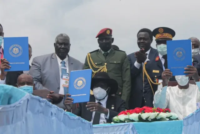 Officials hold up blue folders bearing South Sudan's emblem at a signing ceremony, file photo