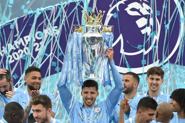 Manchester City players in sky-blue shirts lift the Premier League trophy amid streamers, file photo