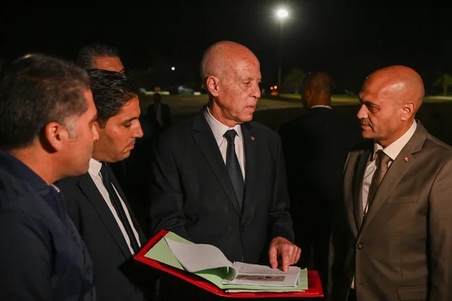 Tunisian President Kais Saied looks at a file surrounded by officials at night, file photo