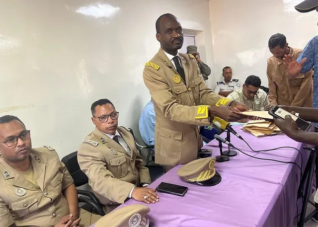An official in uniform hands out envelopes at an aid distribution