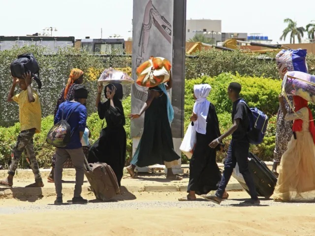 A group of Sudanese walking along a street carrying their bags and belongings, file photo