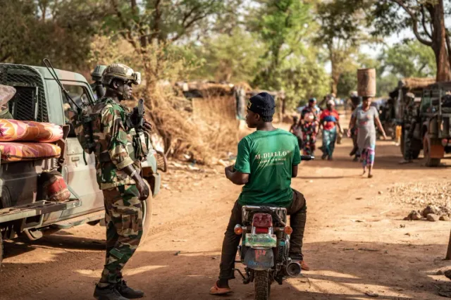 A Senegalese soldier in camouflage and helmet next to a pick-up on a dirt road, illustrative file image