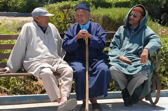 Three elderly men in djellabas sitting on a garden bench, file photo