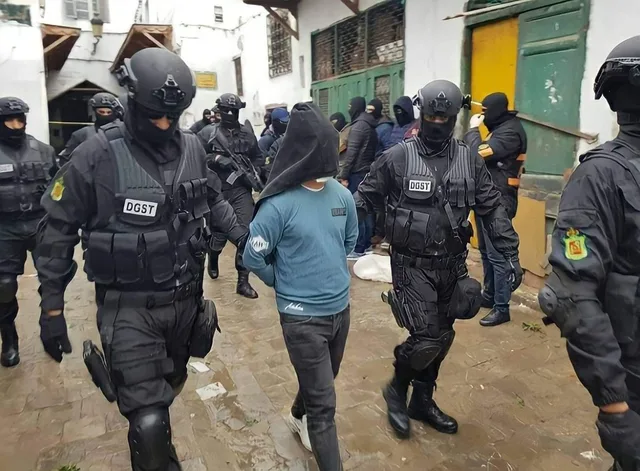 DGST officers escort a hooded suspect during an earlier security operation in Morocco