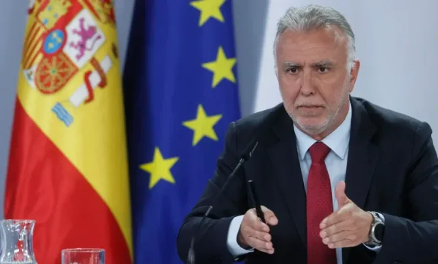Angel Victor Torres speaks at a press conference in front of Spanish and EU flags