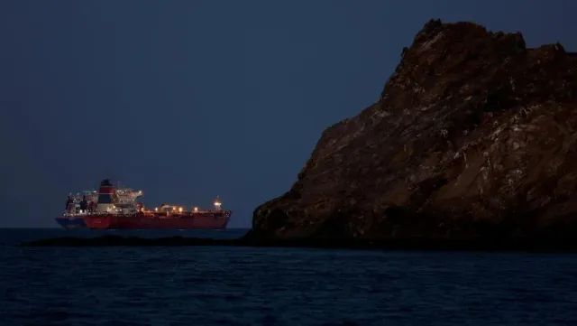 An oil tanker sailing near a rocky coast at dusk, file photo