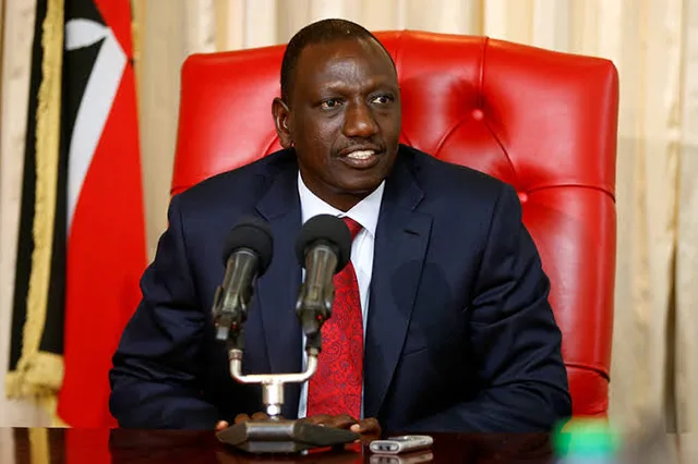 Kenyan President William Ruto speaking in front of two microphones with the Kenyan flag behind him, file photo