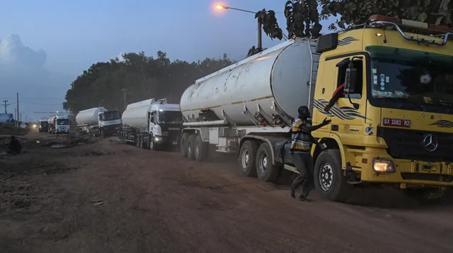A line of fuel tanker trucks on a dirt road at dusk, illustrative file image