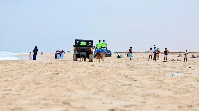 A sandy beach in Nouakchott with walkers and a patrol vehicle