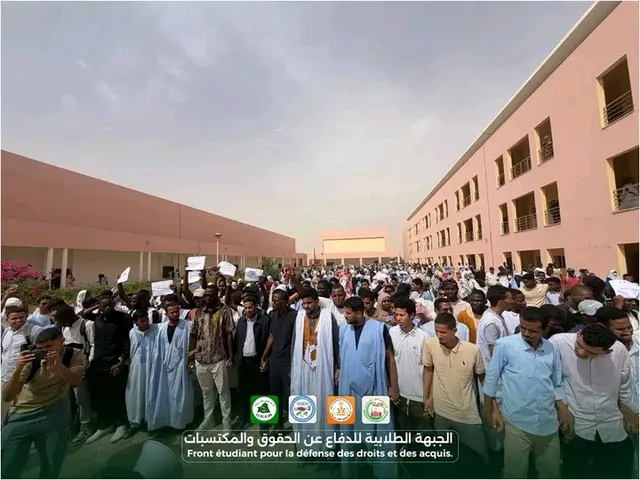 A crowd of students holding placards in the courtyard of a university building