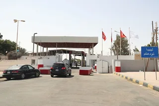 Entrance to a land border crossing between Tunisia and Libya, with cars and a sign reading Libya bids you farewell, file photo