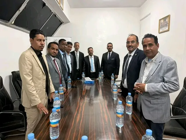 Two delegations standing around a meeting table