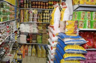 Shop shelves stocked with bags of rice, canned goods and cooking oils