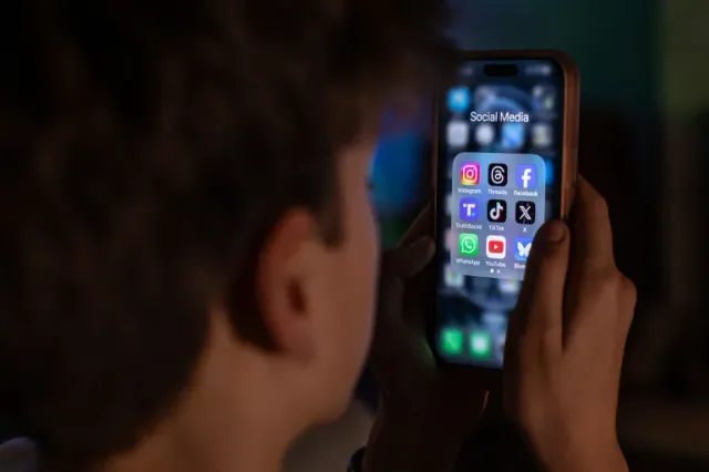 A person holds a phone showing social media apps, file photo