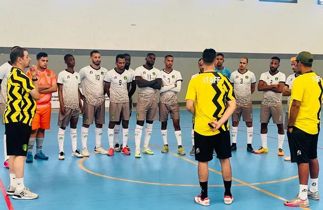 Futsal players in white shirts listening to their coach in a sports hall