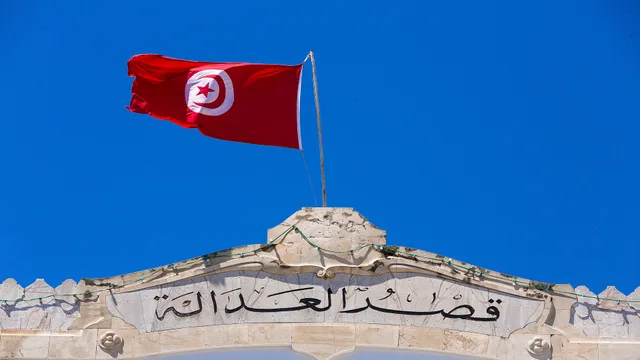 The Tunisian flag flying above a stone facade inscribed "Palace of Justice" in Arabic, file photo