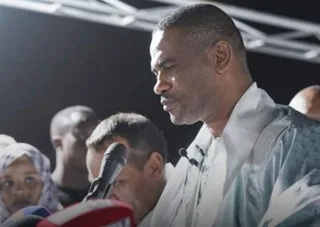 A man speaks into a microphone at an evening event
