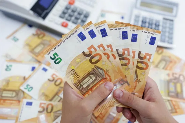 Hands holding 50-euro banknotes in front of two calculators, illustrative file photo
