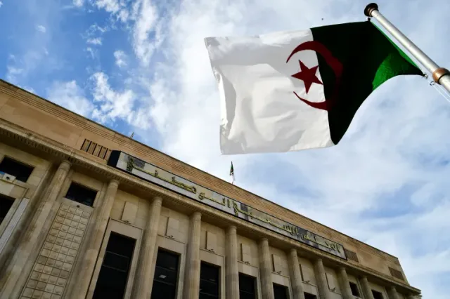 The facade of the National People's Assembly building in Algiers with the Algerian flag