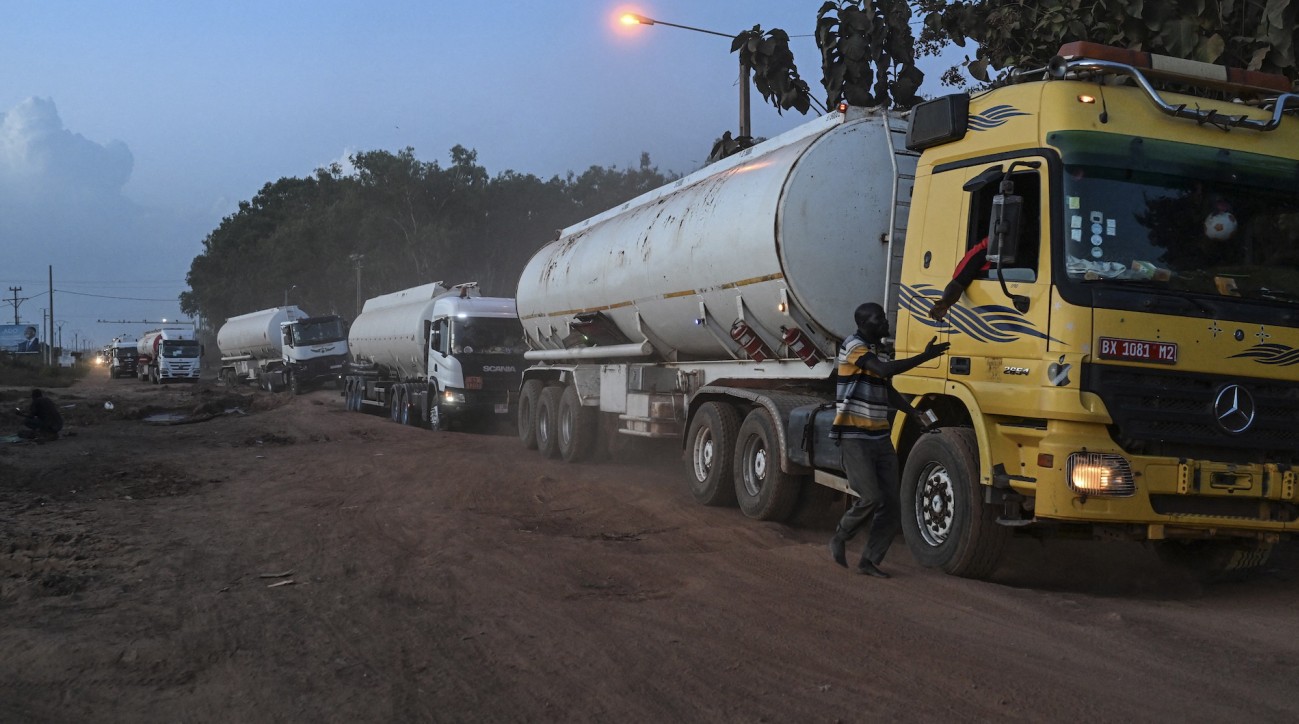 A line of fuel tanker trucks on a dirt road at dusk